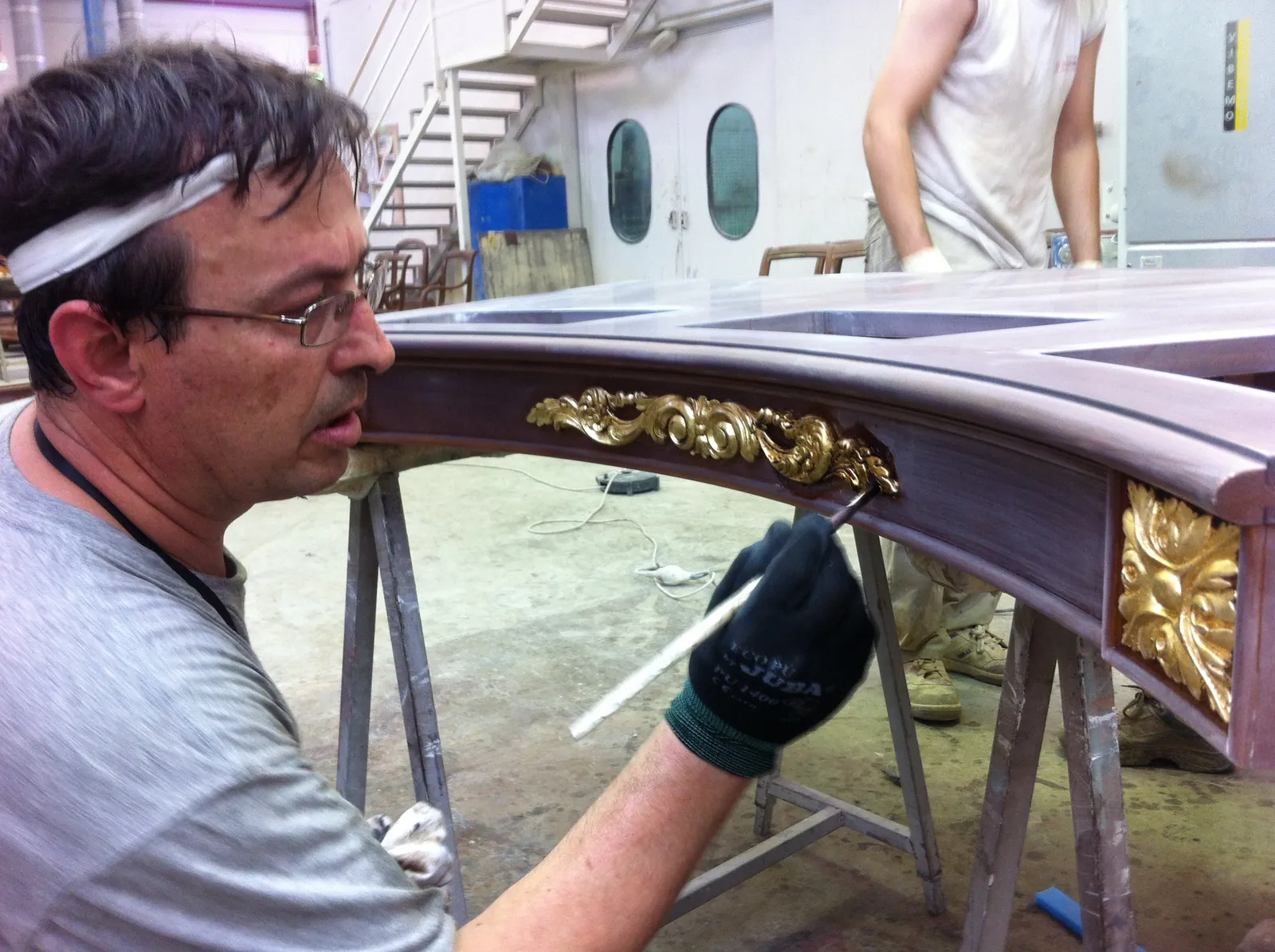 Craftsman hand-applying gilding to a wooden piece